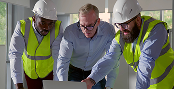 Construction workers and an architect reviewing building plans